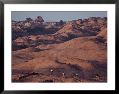 Mountain Bike Riders On Slickrock Trail Near Moab, Utah; Arches National Park Is In The Background by Joel Sartore Pricing Limited Edition Print image