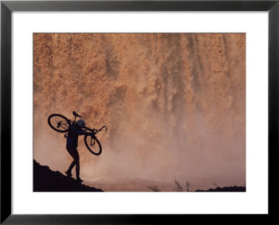 Silhouetted Cyclist Carrying Cycle Past Falls by Bill Hatcher Pricing Limited Edition Print image