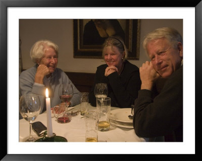 A Family Sits Around The Dinner Table At A Restaurant, Fraueninsel, Chiemsee, Bavaria, Germany by Taylor S. Kennedy Pricing Limited Edition Print image