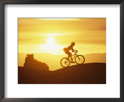A Woman Rides Her Bike In The Sunset With Rock Cliffs In The Background by Dugald Bremner Pricing Limited Edition Print image