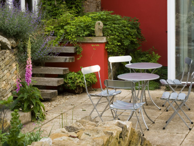 Metal Chairs Surround Circular Table In Front Of Red Wall On Patio (Terrace) by Clive Nichols Pricing Limited Edition Print image