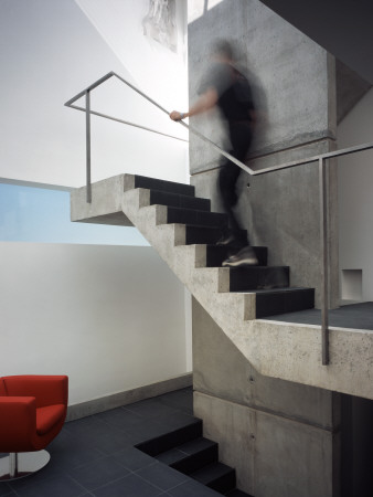 The Tall House Interior Of The Stair Well With Red Chair And Blurred Man On The Stairs by Richard Bryant Pricing Limited Edition Print image