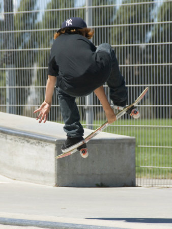 Young Boy Flying Through The Air On A Skateboard, From Behind by Stephen Sharnoff Pricing Limited Edition Print image