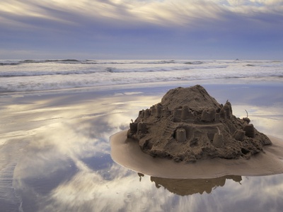 A Sandcastle Being Slowly Washed Away By The Incoming Tide, Cannon Beach, Oregon by Peter Carroll Pricing Limited Edition Print image