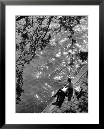 Couple Relaxing On Bank Of Seine Near Notre Dame Cathedral During Lunch Hour by Alfred Eisenstaedt Pricing Limited Edition Print image