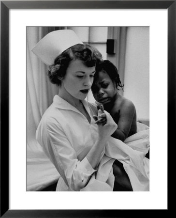 Nurse Holding African American Girl In Her Arms, Examining Her Finger by John Dominis Pricing Limited Edition Print image