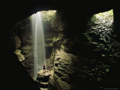Caver Stands In A Beam Of Sunlight In Front Of A Waterfall by Stephen Alvarez Pricing Limited Edition Print image