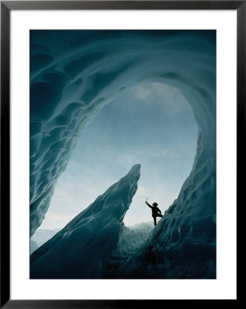 A Climber Raises His Ax In Triumph Near The Opening Of An Ice Cave by George F. Mobley Pricing Limited Edition Print image