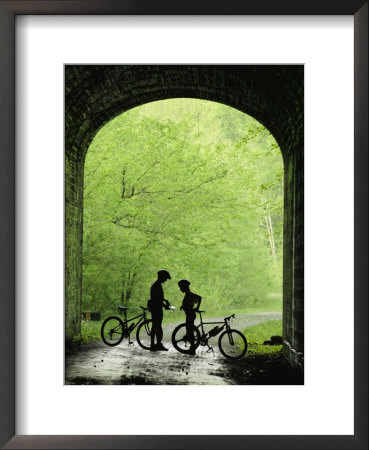 Two Silhouetted Cyclists Stop In A Tunnel On A Bike Trail by Richard Nowitz Pricing Limited Edition Print image