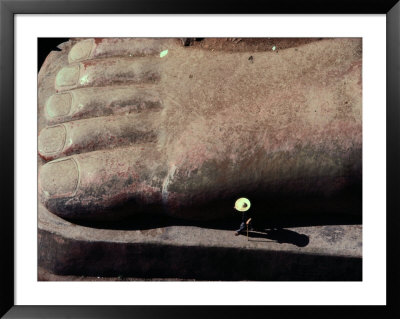 A Person Walks Past The Giant Foot Of Buddha by Jodi Cobb Pricing Limited Edition Print image