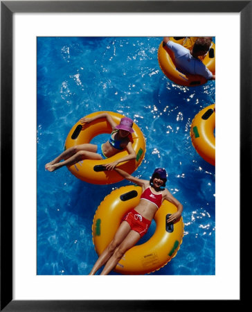 Young Girls Floating In Rubber Rings In Swimming Pool, Gold Coast, Australia by Richard I'anson Pricing Limited Edition Print image