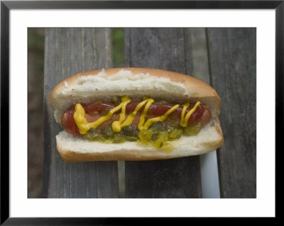 A Hot Dog Is Covered In Condiments Like Mustard, Ketchup And Relish by Stephen Alvarez Pricing Limited Edition Print image