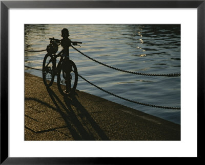 Bicycle Resting On A Railing Along Victoria Harbour As The Sun Sets by Todd Gipstein Pricing Limited Edition Print image