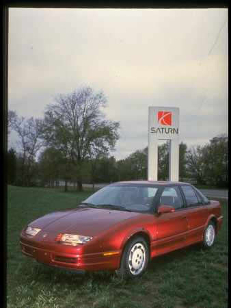 Spiffy Spanking New Red Saturn Sl2 Sports Touring Sedan On Logo Sign, Gm Plant In Spring Hill by Ted Thai Pricing Limited Edition Print image