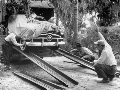 Unloading The New Ford Car, Swathed In Canvas, To Make Advertising Pictures Of The New Model by William Sumits Pricing Limited Edition Print image