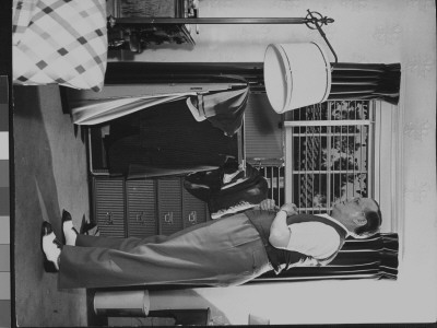 Writer Damon Runyon Trying On Vest With Open Wardrobe Trunk And Other Clothing In Background by Gjon Mili Pricing Limited Edition Print image