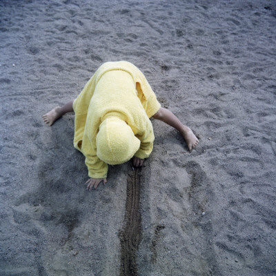 A Child In A Bathrobe Playing On A Beach, Sweden by Mikael Andersson Pricing Limited Edition Print image
