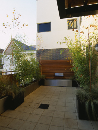 Roof Terrace: Wood And Metal Water Feature With Water Spout Surrounded By Bamboo In Containers by Clive Nichols Pricing Limited Edition Print image