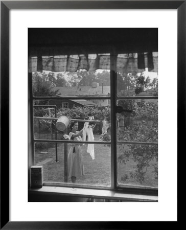 Suburban Housewife Hanging Out A Bit Of Laundry, Seen Through Window In Typical California Home by Loomis Dean Pricing Limited Edition Print image