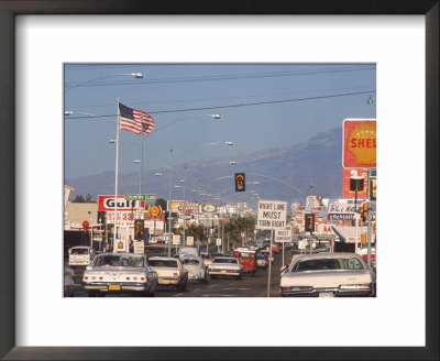 Cars Moving Along Congested Street, Littered With Signs, Billboards And Traffic Directives by Michael Rougier Pricing Limited Edition Print image