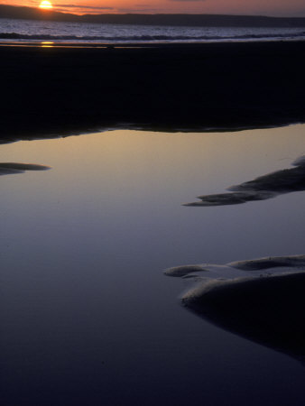 Setting Sun Over The Ocean, With Sky Reflected In Dark Still Water by Stephen Sharnoff Pricing Limited Edition Print image