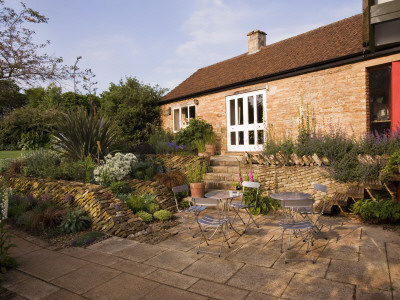 Angles Drystone Wall, Metal Table And Chairs On The Patio At The Back Of The House by Clive Nichols Pricing Limited Edition Print image