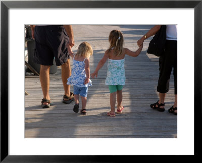 Grandchildren Walk Down A Wooden Pier With Their Grandparents by Stacy Gold Pricing Limited Edition Print image