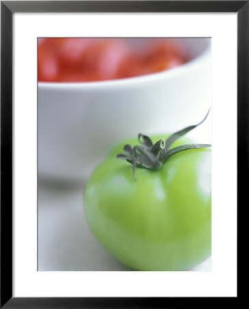 Whole Green Tomato In Front Of A Bowl Of Red Tomatoes by David Loftus Pricing Limited Edition Print image