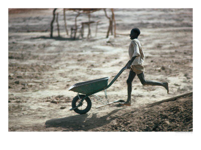 Boy Running With Wheelbarrow, Burkina Faso by Eric Wheater Pricing Limited Edition Print image
