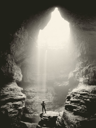A Man Stands In Front Of A Skylit Cave Waterfall by Stephen Alvarez Pricing Limited Edition Print image