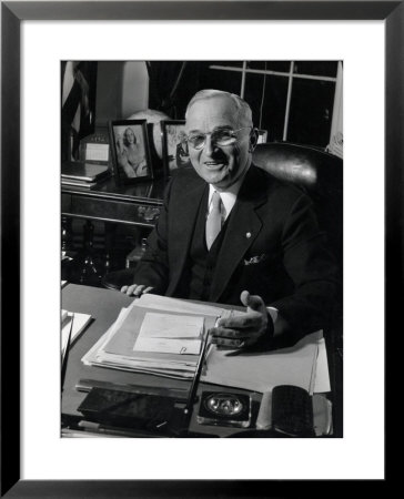 Pres. Harry S. Truman Seated At His Desk In The White House, Family Photographs On Table Behind Him by Gjon Mili Pricing Limited Edition Print image