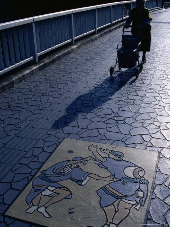 Woman Walking Across Bridge Paved With Tessellated Tiles And Relief Art Of Awa Odori Dancers, Japan by Mason Florence Pricing Limited Edition Print image