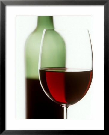 Red Wine Glass With Half-Full Wine Bottle In Background by Joerg Lehmann Pricing Limited Edition Print image