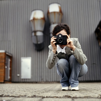 A Young Woman Crouching And Taking A Photograph by Jewgeni Roppel Pricing Limited Edition Print image