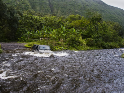 All Terrain Vehicle Drives Through A River In The Waipi'o Valley by Todd Gipstein Pricing Limited Edition Print image