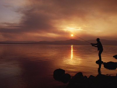 Fly Fisherman Casts His Line Into Yellowstone Lake At Sunset by Tom Murphy Pricing Limited Edition Print image