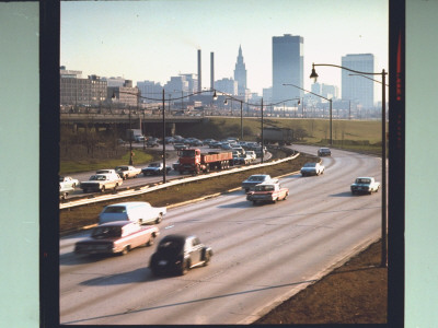 Traffic On Curving Stretch Of Highway With Skyscrapers In Distance by Ralph Crane Pricing Limited Edition Print image