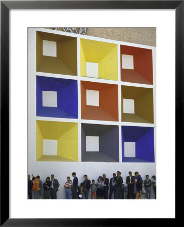 Line Of People Under Building Facade Painted With Brightly Colored Geometric Pattern by John Dominis Pricing Limited Edition Print image