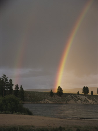 Two Rainbows Arcing Over A Body Of Water by Stephen Sharnoff Pricing Limited Edition Print image