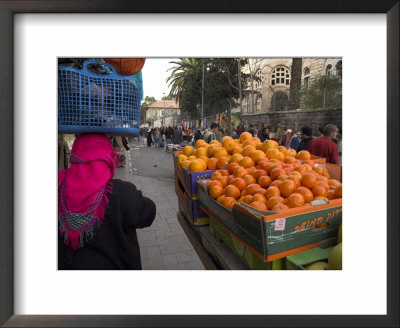 Palestinian Woman In Colourful Scarf And Carrying Bag On Her Head Walking Past An Orange Stall by Eitan Simanor Pricing Limited Edition Print image