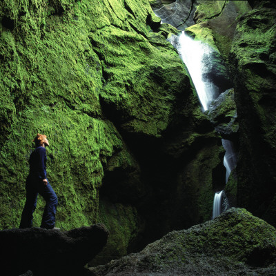 A Person Standing By Mossy Rocks And Looking At A Waterfall, Iceland by Thorsten Henn Pricing Limited Edition Print image