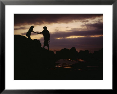 A Man With A Camera Helps A Woman Down Rocks Near Tanah Lot Temple by Eightfish Pricing Limited Edition Print image