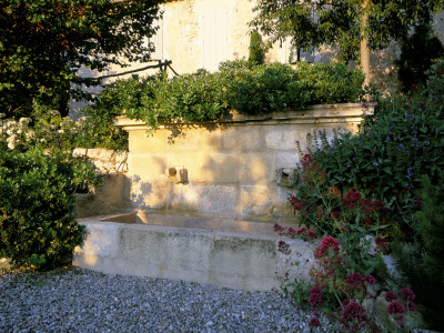 La Chabaude, France, Stone Water Feature On Gravel Terrace With Centranthus Ruber by Clive Nichols Pricing Limited Edition Print image