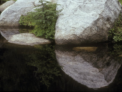 Granite Boulders Reflected In A Calm Mountain Lake by Stephen Sharnoff Pricing Limited Edition Print image