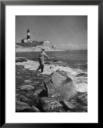 Man Fishing Off Montauk Point. Montauk Lighthouse Visible In Background by Alfred Eisenstaedt Pricing Limited Edition Print image