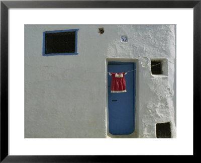 Child's Dress Hangs In Front Of A Blue Door In A Whitewashed House by James L. Stanfield Pricing Limited Edition Print image