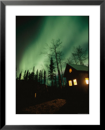 Aurora Borealis Fills The Sky Over A Warmly Lit Cabin by Rich Reid Pricing Limited Edition Print image