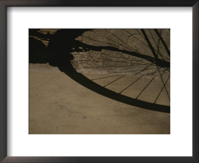 A Bicycle Wheel Casts A Shadow On A Wall And Sidewalk In Siena by Raul Touzon Pricing Limited Edition Print image