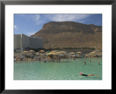 People Floating In The Sea And Hyatt Hotel And Desert Cliffs In Background, Dead Sea, Middle East by Eitan Simanor Pricing Limited Edition Print image