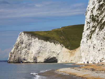 Holidaymakers Wander Along The Beach At Durdle Door, Towards Bats Head Cliff, Dorset, England, Uk by Adam Burton Pricing Limited Edition Print image